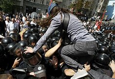 Protestuotoja lipa per policininkų galvas.