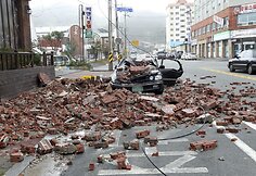 Vėjo ir stiprios liūties neatlaikiusi dalis sienos nugriuvo ant automobilio.