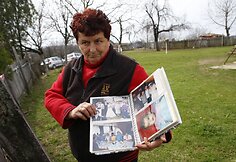Moteris rodo nuotraukų albumą su kaimo gyventojais