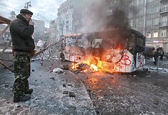 Protestuotojas prie sudegusio autobuso Kijeve