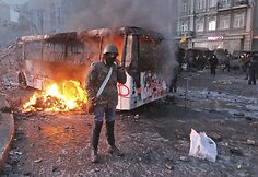 Protestuotojas prie sudegusio autobuso Kijeve