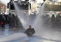 Vandens srovės parblokštas ir nusmukusiomis kelnėmis protestuotojas.