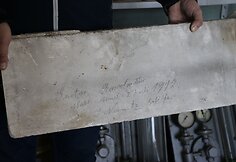 Stogo šiltinimo plokštė, kurios viduje – pluoštas. 1912 m. darbininkai įsiamžino, palikdami savitą pėdsaką