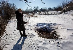 Marjinkos gyventoja Oksana rodo &scaron;alia tako sprogusio artilerijos sviedinio duobę