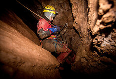 Speleologė specialios įrangos pagalba leidžiasi į urvo gilumą