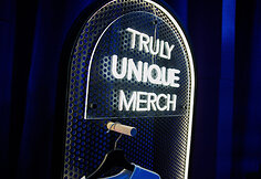 „Truly Unique Merch“ stendas