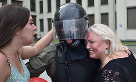 Protestuotojai glėbesčiuojasi su prie Baltarusijos vyriausybės rūmų skydus nuleidusiais saugumo pareigūnais