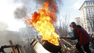 An anti-government protester moves a burning tyre at a barricade in Kiev February 21, 2014. Violence flared again in Kiev on Friday as Ukraine's opposition politicians pondered a draft deal with Russian-backed President Viktor Yanukovich which EU foreign ministers brokered to resolve the country's p
