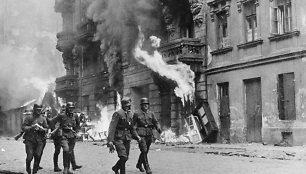 Vokiečių kareiviai 1943 m. eina pro padegtą Varšuvos getą, kuris po sukilimo buvo sudegintas iki pamatų 