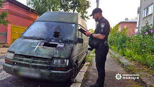 Ukrainos policijos pareigūnas apžiūrinėja per padegimą apgadintą automobilį.