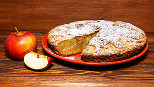 Apples and freshly baked apple pie on a rustic background of dark wood.