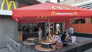 Maskvoje žmonės sėdi prie uždaryto „McDonald's“ restorano stalų.