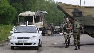 Vyrai su baltais skudurėliais atomobiliu važiuoja pro separatistų patikrinimo postą Luhanske