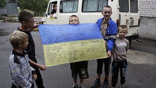 Vaikai rodo Ukrainos vėliavą su savanorių karių para&scaron;ais