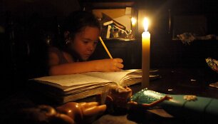 Venesuela taupo elektros energiją, dėl to ji tiekiama ribotą laiką. Mergaitė ruo&scaron;ia namų darbus prie žvakių &scaron;viesos.