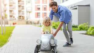 Tėtis moko sūnų vairuoti žaislinį automobilį