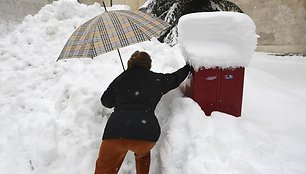 Moteris bando įmesti laišką į pašto dežutę.