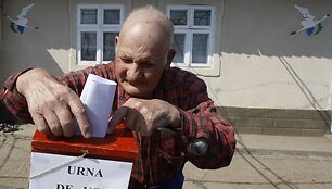Senukas meta rinkimų lapelį į mobilią balsavimo dėžutę.