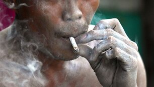 Rūkantis žmogus ant kurio kūno pasidengę degūs milteliai