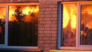 Liepsnos atspindžiai gretimų namų languose.