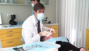 Gydytojas periodontologas apžiūri dantis.