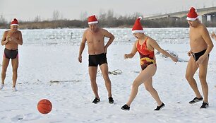 Kinų &bdquo;ruoniai&ldquo;, pasipuo&scaron;ę kalėdinėmis kepurėmis, kamuoliu žaidžia sniege.