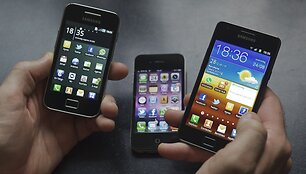 Vyras rankose laiko &bdquo;Samsung Galaxy S II&ldquo; (d.) ir &bdquo;Galaxy Ace&ldquo; i&scaron;maniuosius telefonus. Fone &ndash; &bdquo;Apple&ldquo; telefonas &bdquo;iPhone 4&ldquo;.