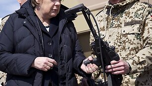 Vokietijos kanclerė Angela Merkel laiko kulkosvaidį.