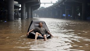 Vyras plaukioja ant pripučiamo fotelio apsemtose miesto gatvėse.