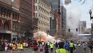 Bostono maratono dalyviai bėga link fini&scaron;o, kairėje pusėje matomas prasidėjęs sprogimas.