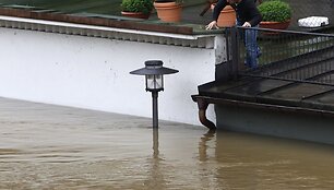 Vyras nuo namo stogo žiūri į apsemtą Pasau miesto gatvę.