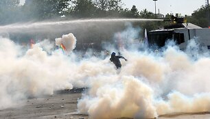 Tarp a&scaron;arinių dujų bėgantis protestuotojas