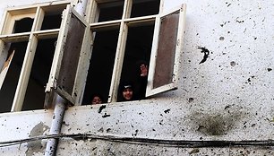 Vaikai žiūri per apgadintą mokyklos langą
