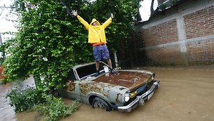 Ant seno automobilio užlipęs vyras pozuoja fotografui.