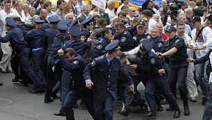 Policininkai bėga nuo protestuotojų.