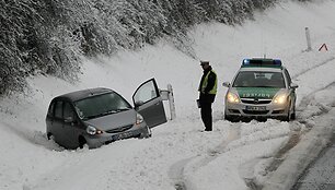 Policininkas stovi &scaron;alia nuo kelio nuslydusio automobilio