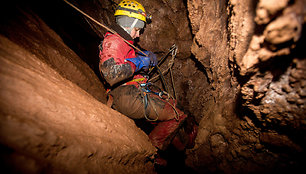 Speleologė specialios įrangos pagalba leidžiasi į urvo gilumą