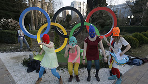 Members of the punk group Pussy Riot, including Nadezhda Tolokonnikova in the aqua balaclava, center, and Maria Alekhina in the red balaclava, left, perform next to the Olympic rings in Sochi, Russia, on Wednesday, Feb. 19, 2014. Cossack militia attacked the punk group with horsewhips earlier in the