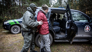 Pasieniečiai &scaron;alia Piesčių kaimo (Varėnos r.) į tarnybinį automobilį sodina sulaikytą migrantą 