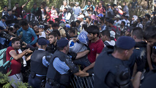 Migrantai Tovarnike braunasi pro pareigūnų užtvarą.