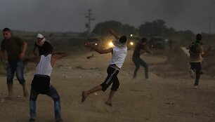 Palestiniečiai mėto akmenis į Izraelio pareigūnus.
