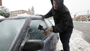 Vyras gramdo apledėjusius automobilio stiklus.