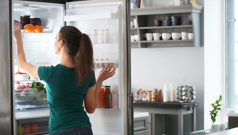 Moteris prie šaldytuvo.