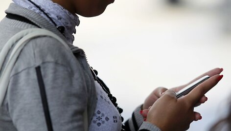 Moteris su telefonu rankose
