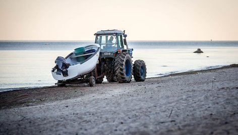 Į jūrą žvejų valtis nuleidžiama iš traktoriaus priekabos