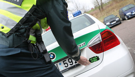 Kelių policininkas ant automobilio klijuoja lipduką „Aš neimu kyšio“