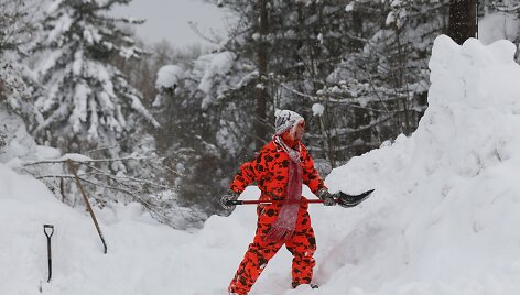 Moteris valo sniegą prie įvažiavimo į savo kiemą
