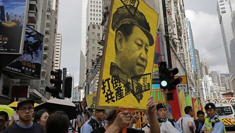 Protestuotojas laiko Xi Jinpingo plakatą