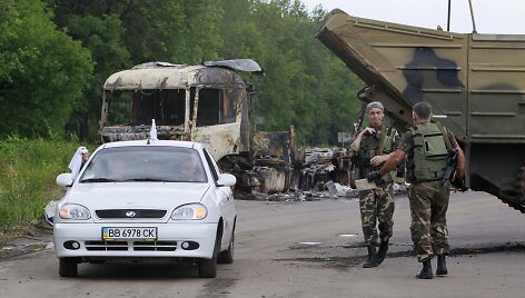 Vyrai su baltais skudurėliais atomobiliu važiuoja pro separatistų patikrinimo postą Luhanske