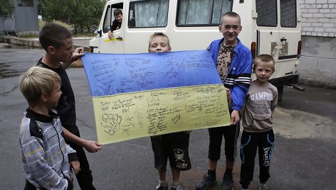 Vaikai rodo Ukrainos vėliavą su savanorių karių parašais